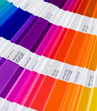 Home 14 Close-up of a color swatch book displaying a range of bright colors, ideal for printing and cutting projects, with each shade—blue, purple, pink, red, and orange—labeled by numerical codes on crisp white strips.