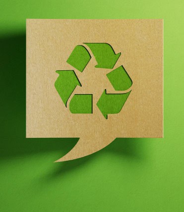 Home 13 A brown cardboard speech bubble with a cutout recycling symbol, crafted through precise cutting and printing, displayed on a green background.