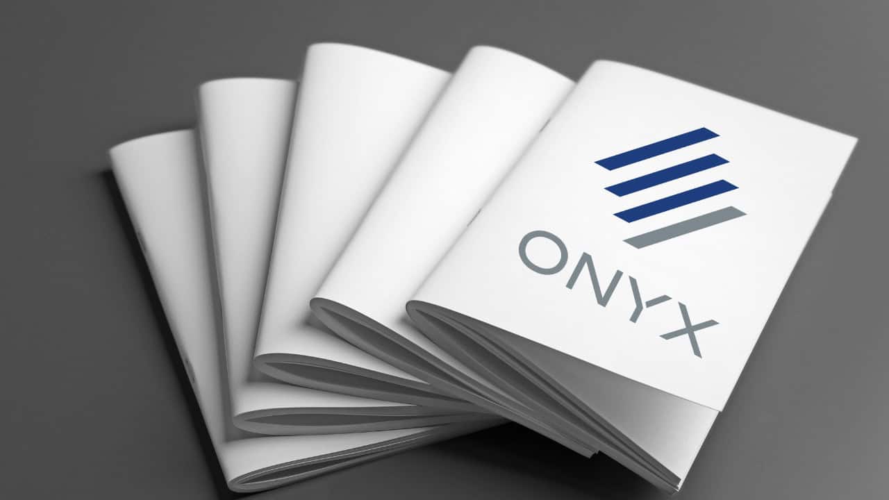 A stack of folded white brochures, produced with precision printing and featuring the ONYX logo and stylized blue and gray bars on the cover, arranged neatly on a gray surface.