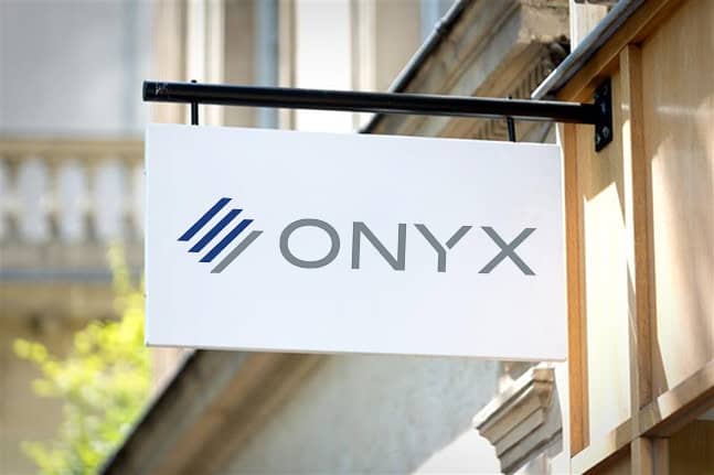 A white rectangular sign with the word "ONYX," referencing Onyx Graphics and their cutting-edge RIP software, and a blue striped logo is mounted on the exterior wall of a building.